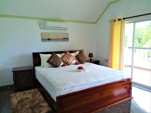 a bedroom with a large bed with white sheets at Wyn Villa in Anse Possession