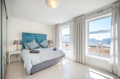 a bedroom with a bed with a blue headboard and windows at 3 Canterbury Square in Cape Town