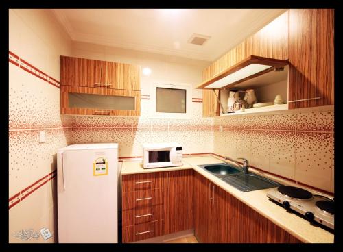 Una pequeña cocina con nevera y fregadero. en Taraf Yanbu, en Yanbu
