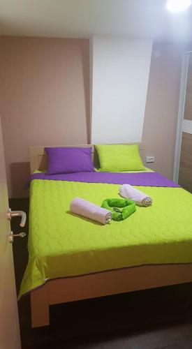 a bed with green sheets and two towels on it at Pestani Apartment in Peštani