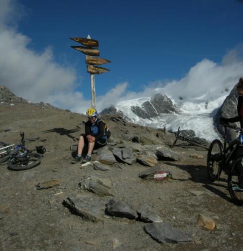 a person sitting next to a sign on a mountain at Hotel Garnì COSTANZA in Livigno
