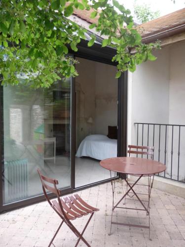 a patio with a table and two chairs and a bed at Beaune Hôtel in Beaune