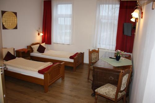 a room with two beds and a table and chairs at Fürstenhof Landgasthaus & Hotel in Erfurt