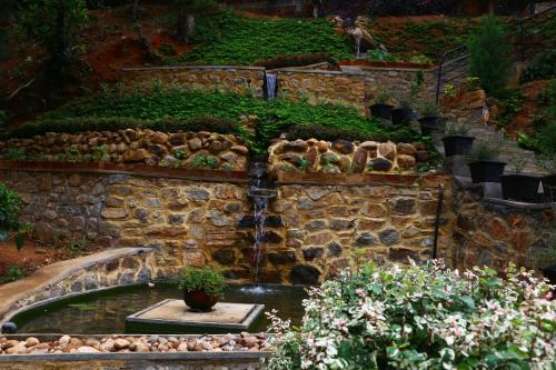 a stone wall with a water fountain in a garden at Train View Chalet in Bandarawela