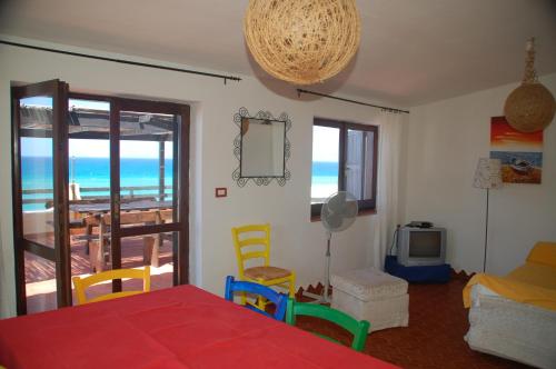 uma sala de estar com uma mesa e cadeiras e uma televisão em Villa Alabe - Waterfront Apartments in Bosa Porto Alabe em Tresnuraghes