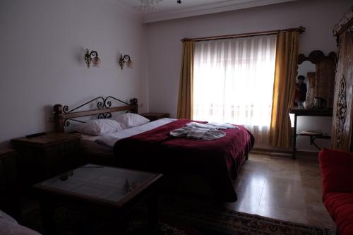 a bedroom with a bed with a red blanket and a window at Anatolia cave hotel Pension in Goreme
