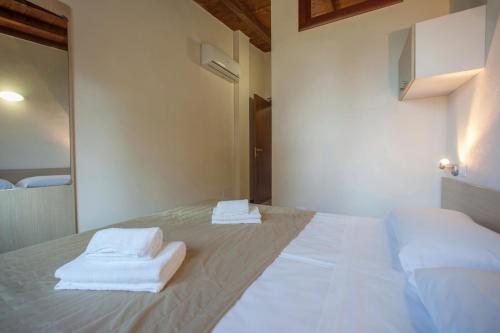 a white bed with towels sitting on top of it at The Garda Village in Sirmione