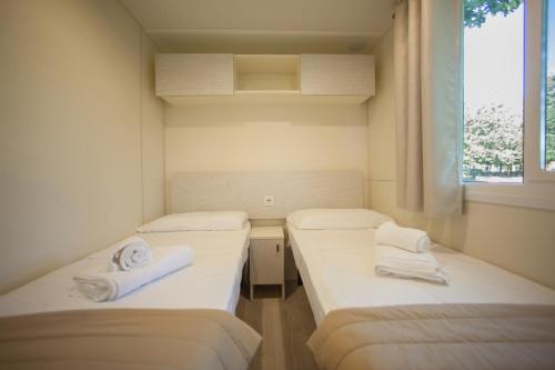 two beds in a small room with a window at The Garda Village in Sirmione