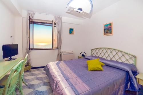 a bedroom with a bed with a yellow pillow and a window at La Casetta in Amalfi