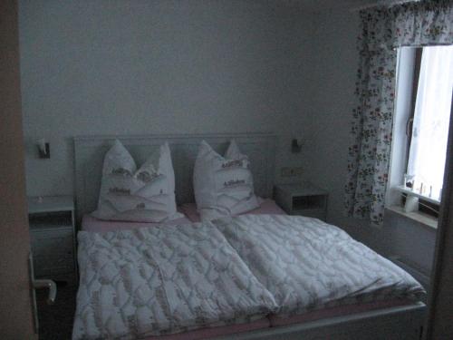 NeudorfにあるFerienhaus Kohlmeiseのベッドルーム1室(白いシーツと枕のベッド1台付)