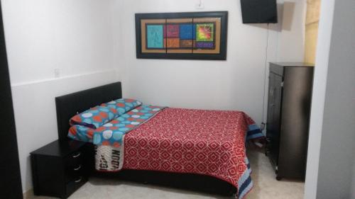 1 dormitorio con 1 cama y una foto en la pared en Apartaestudios El Cable, en Manizales