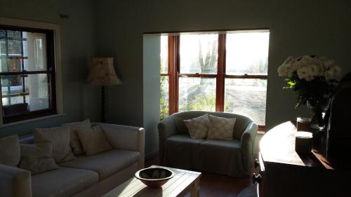 a living room with a couch and a chair and windows at Rings Coach House Retreat in Carlow