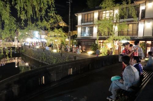 a group of people sitting on a bench at night at Morizuya in Toyooka