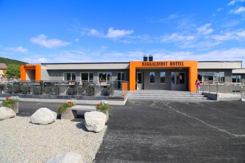 a building with an orange front with a woman standing outside at Bakkalandet Hotel in Kolvereid