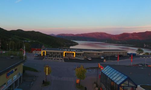 a building with a parking lot in front of a lake at Bakkalandet Hotel in Kolvereid