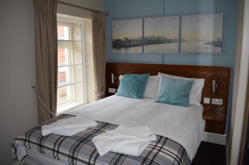 Schlafzimmer mit einem Bett mit weißer Bettwäsche und blauen Kissen in der Unterkunft Woolpack Pub & Kitchen in Wainfleet All Saints