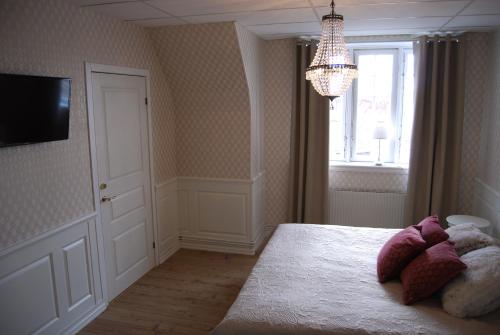 a bedroom with a bed and a window and a chandelier at Halmstad Hotell & Vandrarhem Kaptenshamn in Halmstad