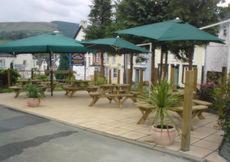a patio with picnic tables and umbrellas at Belle Vue Hotel in Llanwrtyd Wells