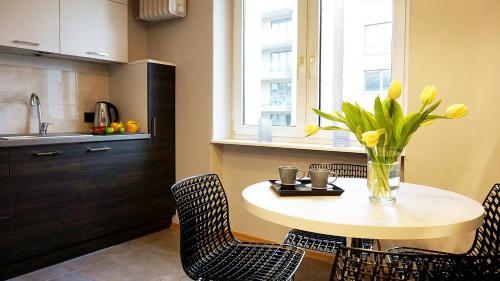 オルシュティンにあるDK Apartament Grunwaldzkiの花瓶の黄色い花が飾られた台付きキッチン