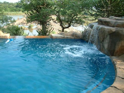 een groot zwembad met een waterval in een achtertuin bij River Hill Lodge in Komatipoort