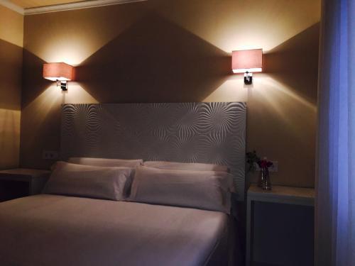a bedroom with a bed with two lamps on the wall at Hostal Los Castañuelos in Candeleda