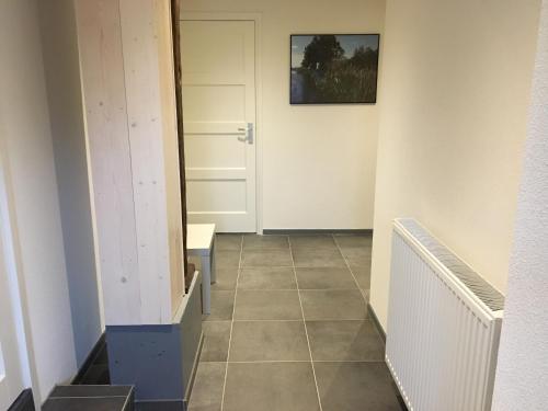 a hallway with a door and a tiled floor at Bed & Bike De Hofstee in Giethoorn