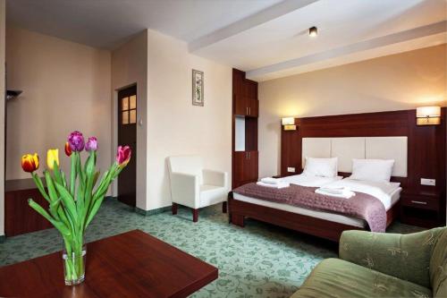 une chambre d'hôtel avec un lit et un vase de fleurs dans l'établissement Hotel Młyn, à Lublin