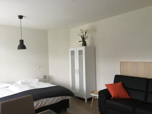 1 dormitorio con 1 cama, 1 sofá y 1 silla en Bed & Bike De Hofstee, en Giethoorn