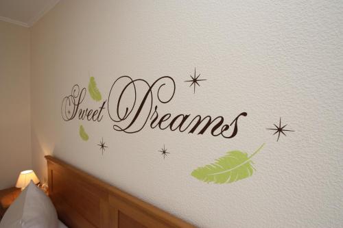 a bedroom with a wall with a sign that reads sweet dreams at Gasthaus Pension Geimer in Plütscheid
