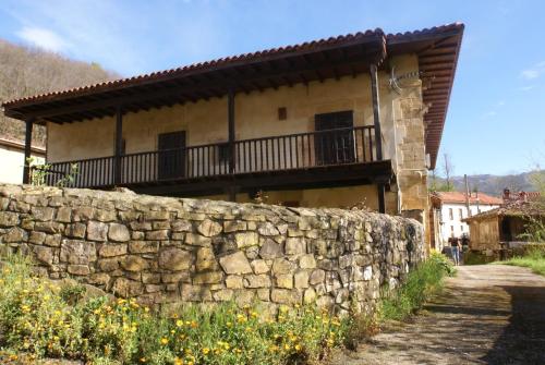 a stone wall in front of a building with a balcony at Palacio Rural de Inguanzo de Cabrales in Inguanzo