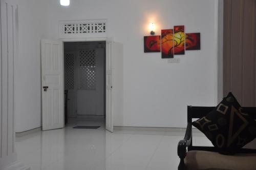 a white room with a chair and a painting on the wall at Bon Voyaage Tourist Inn in Trincomalee
