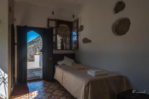 1 dormitorio con 1 cama y puerta con ventana en Dar Wadada, en Chefchaouen