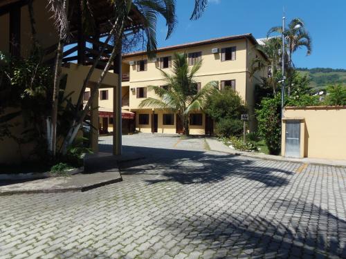 a building with palm trees in front of a driveway at Pousada do Cardoso in Angra dos Reis