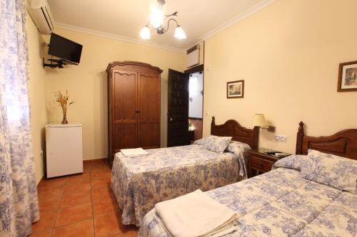 a hotel room with two beds and a television at Hostal Rocio in Sanlúcar la Mayor
