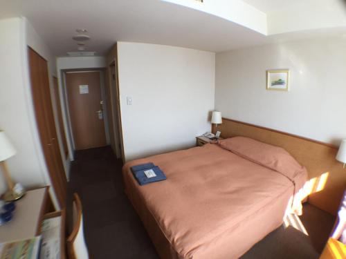 a bedroom with a bed with a blue book on it at Hotel Okhotsk Palace in Mombetsu