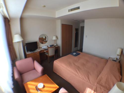 a hotel room with a bed and a chair and a desk at Hotel Okhotsk Palace in Mombetsu