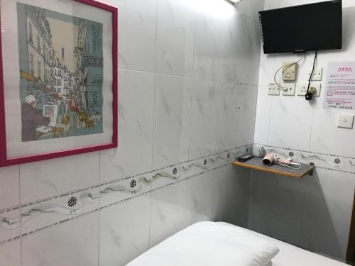 a room with a bed and a television on a wall at Beverly Guest House in Hong Kong