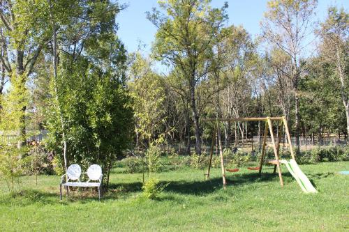 a playground with two chairs and a swing at Gîte Du Puy de l'étang in Laruscade