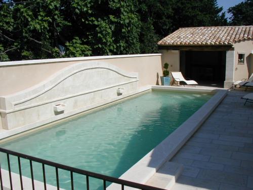 a swimming pool next to a fence and a house at Chambre d'hôte Anais in Eyguières