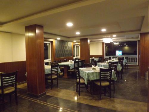 a dining room with tables and chairs in a restaurant at The Majestic Crown in Ooty