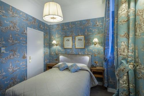 a bedroom with blue wallpaper and a bed with two pillows at Grand Hôtel de L'Univers Saint-Germain in Paris