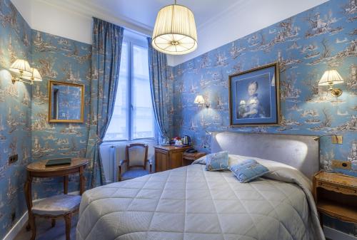 a bedroom with blue wallpaper with a bed and chairs at Grand Hôtel de L'Univers Saint-Germain in Paris