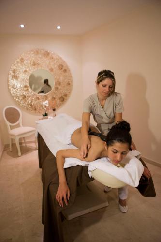 a woman sitting on a bed with a woman cutting a girls hair at Gloria Palace Royal Hotel & Spa in Puerto Rico de Gran Canaria