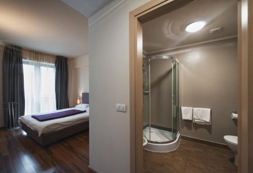y baño con cama y ducha acristalada. en Hotel Hemingway Residence en Bucarest
