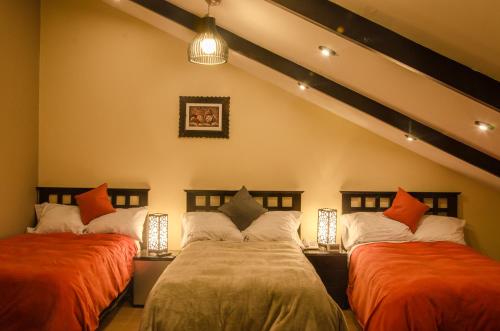 1 dormitorio con 2 camas y almohadas de color naranja y blanco en Cusco Bed and Breakfast, en Cusco