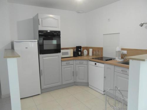 une cuisine avec des appareils électroménagers blancs et des armoires blanches dans l'établissement Les Hirondelles de la Baie, à Vains