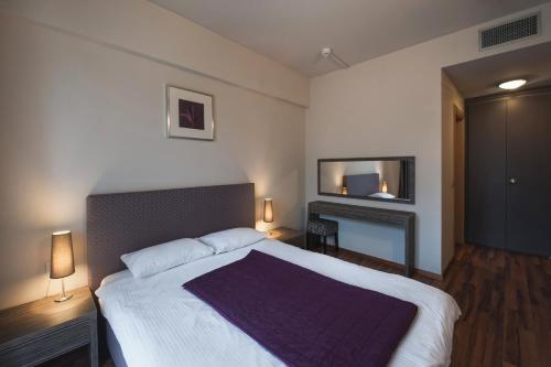 um quarto com uma cama grande e uma televisão em Hotel Hemingway Residence em Bucareste