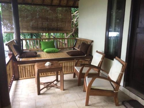 a porch with a couch and a table and chairs at Jukung Bali Bungalow in Amed