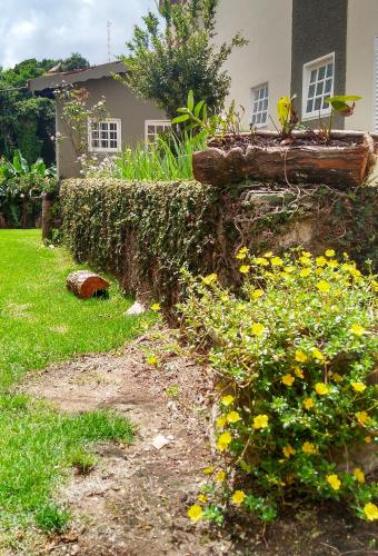 a garden with yellow flowers in front of a house at Hotel Santiago in Lindóia