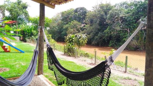 a couple of hammocks in a yard with a river at Hotel Santiago in Lindóia